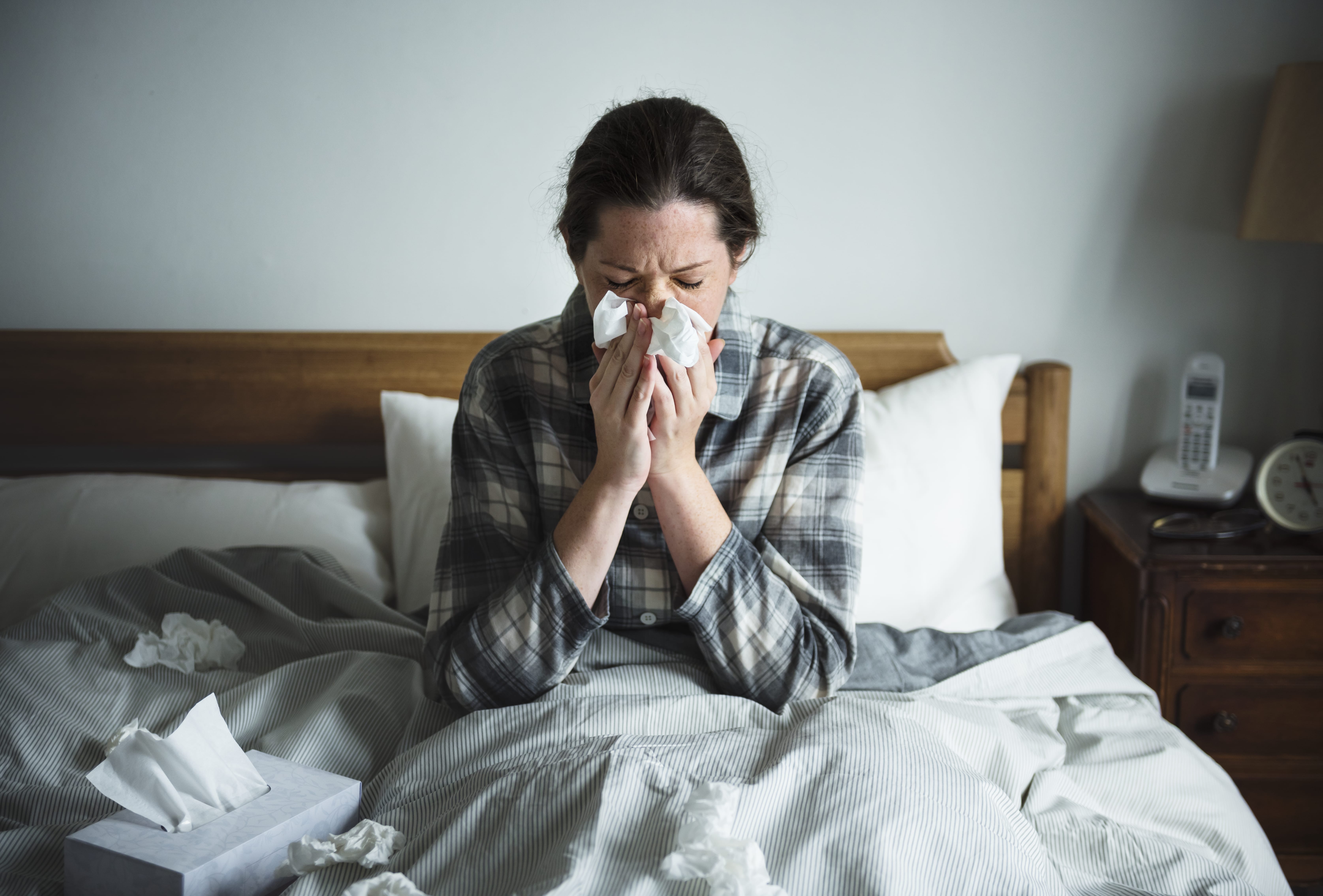 A woman sick in bed without a flu vaccination